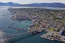 Luftbild einer auf einer Insel gelegenen, dicht bebauten Stadt. Auf die Insel führt eine Brücke. An der Küste befinden sich Hafenanlagen.