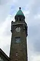 Pegelturm der St. Pauli-Landungsbrücken in Hamburg mit Anzeigeskala. Das runde Zifferblatt zeigt in diesem Fall die Uhrzeit an.