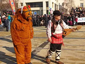 Als Bär und Bärenzähmer verkleidete bei den Internationalen Maskenspielen in Pernik 2017. Rechts ist die Folkloregeige Bulgariens zu sehen - Gadulka