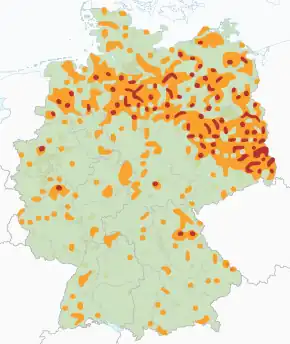 Eine Karte Deutschlands, auf der zahlreiche verstreute orangefarbene Flecken die Wolfsnachweise darstellen und kleinere rote Flecken, vor allem in Nord- und Ostdeutschland, die nachgewiesenen Wolfsreproduktionen zeigen