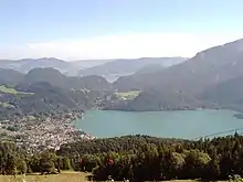 Blick ins Tal über die Sausteigalm auf St. Gilgen und das Westende des Wolfgangsees. Hinten: Mondsee, links: Mondseeberg, Roßmoos, Hochplettspitz; rechts: Fuß des Schafbergs; im Vordergrund: die alte Seilbahn (2005)