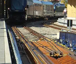 Bahnhof Zweisimmen: Ein auf Normalspur vor einer der beiden Umspuranlagen stehender GPX-Zug; am Ende eine MOB-Lok, die den Zug durch die Anlage und weiter nach Montreux schieben wird. Die BLS-Lok, die den Zug von Interlaken Ost brachte, ist durch die Anlage weggefahren.