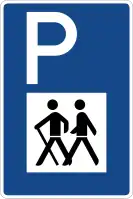 Schild mit einem blauen Hintergrund, oben links ein weißes P. Darunter mittig ein weißes Quadrat mit zwei vereinfacht dargestellten gehenden Menschen.