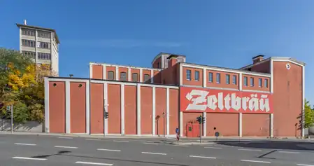 Rotes Brauerei-Gebäude mit der Aufschrift „Zeltbräu“ an einer Straße