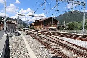 Die abgestellte MOB-Lok, die den Zug nach Montreux schieben wird, wartet am Nordkopf des Bahnhofs auf einem für beide Umspuranlagen benutzten Meterspur-Stumpfgleis. Rechts unten u. rechts: Ausfädelstellen aus Vierschienengleisen.