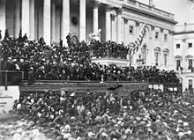 A large crowd in front of a large building with many pillars