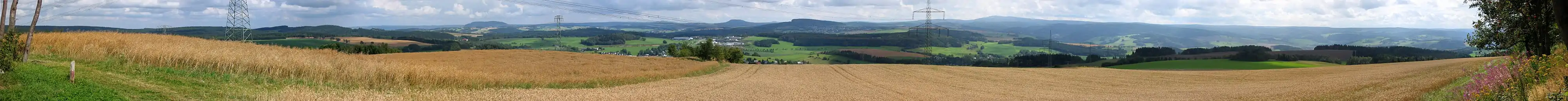 Panoramo de proksimaj bazaltaj montoj Pöhlberg (832 m.s.m.), Jelení hora (993 m.s.m.), Bärenstein (897 m.s.m.), Velký Špičák (965 m.s.m.) kaj Scheibenberg (807 m.s.m.). Dekstre de Fichtelberg (1215 m.s.m.).