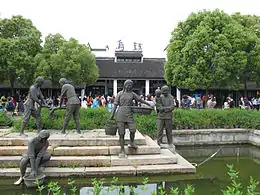 Riverbordaj skulptaĵoj kun la karakteroj "Wuzhen" en la fono