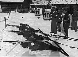 Suomen sotilaspartiohiihtojoukkue Garmisch-Partenkirchenin kisojen ampumapenkalla. Sijoitus Suomen joukkueella oli toinen. Kersantti Olli Remes ylinnä ampumapenkalla olevista.