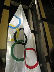 Wite flage mei fiif ringen, as symboal foar de Olympyske Spullen.