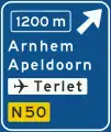 K2: Foarpaadwizer by de autodyk del foar ôfslaande rjochting, mei ôfstânoantsjutting, ôfritnûmer, ynterlokale doelen (boppeste doel = ôfritnamme), ferwizing nei loftthaven en dyknûmer fan net-autodyk