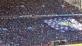 Lucht leanúna Aston Villa i Holte End de chuid Villa Park, ag fógairt gurb iad "12ú fear" na foirne iad.